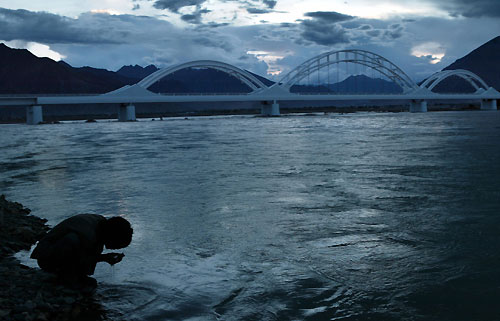 A Tibetan washes his face beside the Lhasa river near the Lhasa railway bridge, July 1, 2006. China opened the world's highest railway on Saturday. Picture taken July 1, 2006. [Reuters]