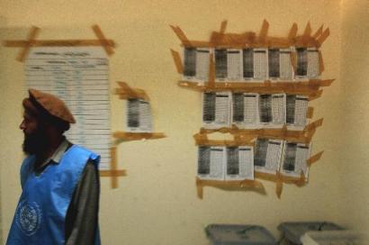 An Afghan electoral worker stands near election results posted on the wall at a counting center in Kabul, Afghanistan, on Tuesday, Oct. 19. 2004. Interim leader Hamid Karzai is certain to win the country's landmark presidential election, his campaign spokesman said Tuesday, after early returns gave him a commanding lead over his rivals. With more than one-quarter of the votes from the Oct. 9 ballot counted, Karzai has captured 60.8 percent. His closest challenger, former Education Minister Yunus Qanooni, trails with 18.3 percent. [AP]