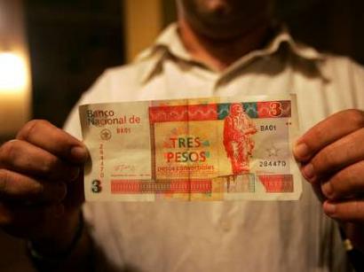 A Cuban waiter holds a three convertible Cuban Peso note, with an image of late guerrilla leader Ernesto 'Che' Guevara, in Havana, October 25, 2004. Cuban President Fidel Castro, seeking to rid his country of the currency of his arch-enemy, said on Monday Cuba was ending circulation of the U.S. dollar as of November 8 in response to tightened American sanctions. [Reuters]