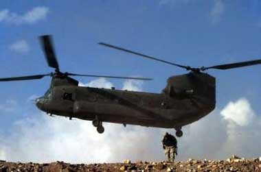 A U.S. Chinook helicopter lands as a U.S. soldier covers his face from dust in the village of Jegdelic, about 90 km (56 miles) southwest of Kabul in this December 24, 2004 file photo. Nine people were killed in Afghanistan April 6, 2005 when a CH-47 crashed during severe weather, the U.S. military said. Picture taken December 24, 2004.