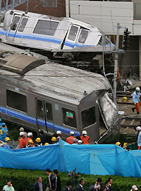 Injured people are tended to after a derailed commuter train smashed into an apartment building in Amagasaki, western Japan April 25, 2005, killing two people and injuring many others, reports said. Nearly 140 people have been hurt, reports said. 