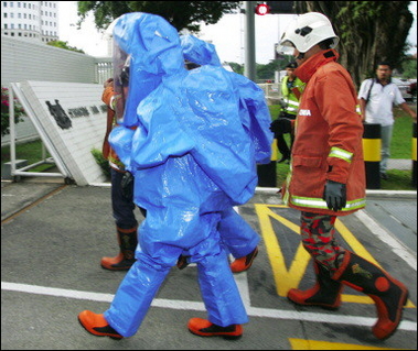 Members of the Malaysian Fire and Rescue Department dressed in chemical suits enter the Singaporean Embassy in downtown Kuala Lumpur.