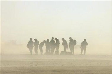 U.S army soldiers stand in the sand while waiting for a helicopter landing at Forward Operation Base Ramagen in Tikrit, Iraq, October 23, 2005.