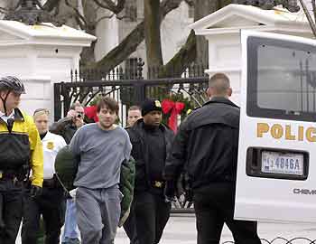 A man identified as Shawn A. Cox, 29, of Arkansas is led away by U.S. Secret Service agents after climbing over the fence at the White House in Washington December 4, 2005. President George W. Bush and First Lady Laura Bush were both in the White House at the time. [Reuters]