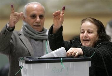 Raheel Mariam, of Sterling Heights, right, raises her ink-stained finger while voting as her husband Gorgees Marcos, left, looks on at the Iraqi national elections voting center in Farmington Hills, Mich., Tuesday, Dec. 13, 2005.