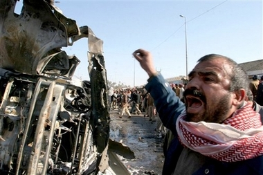 An Iraqi man cries out standing next to a destroyed car at the site of a bomb explosion in Kufa, 160 kilometers (100 miles) south of Baghdad, Iraq, Saturday, Dec. 30, 2006. A bomb planted on a minibus killed 17 people in a fish market in Kufa, while police imposed curfews in some Sunni areas to prevent any outbreak of violence after Saddam Hussein's execution. (AP 