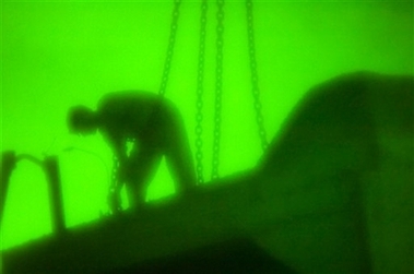 In this photo released by U.S. Army, an Iraqi contractor attaches chains to a concrete barrier so that a crane can lift it into place alongside a road in the Sunni Muslim quarter of Azamiyah, Baghdad, Iraq, Tuesday, April 10, 2007. 